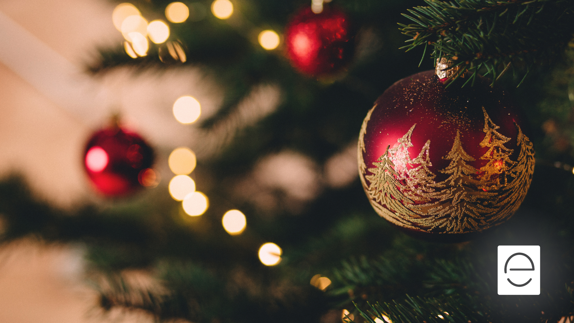 A close up of a christmas tree with red and gold ornaments and lights.