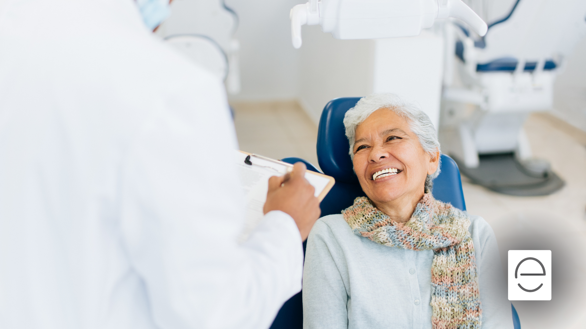 An elderly woman is smiling while sitting in a dental chair.