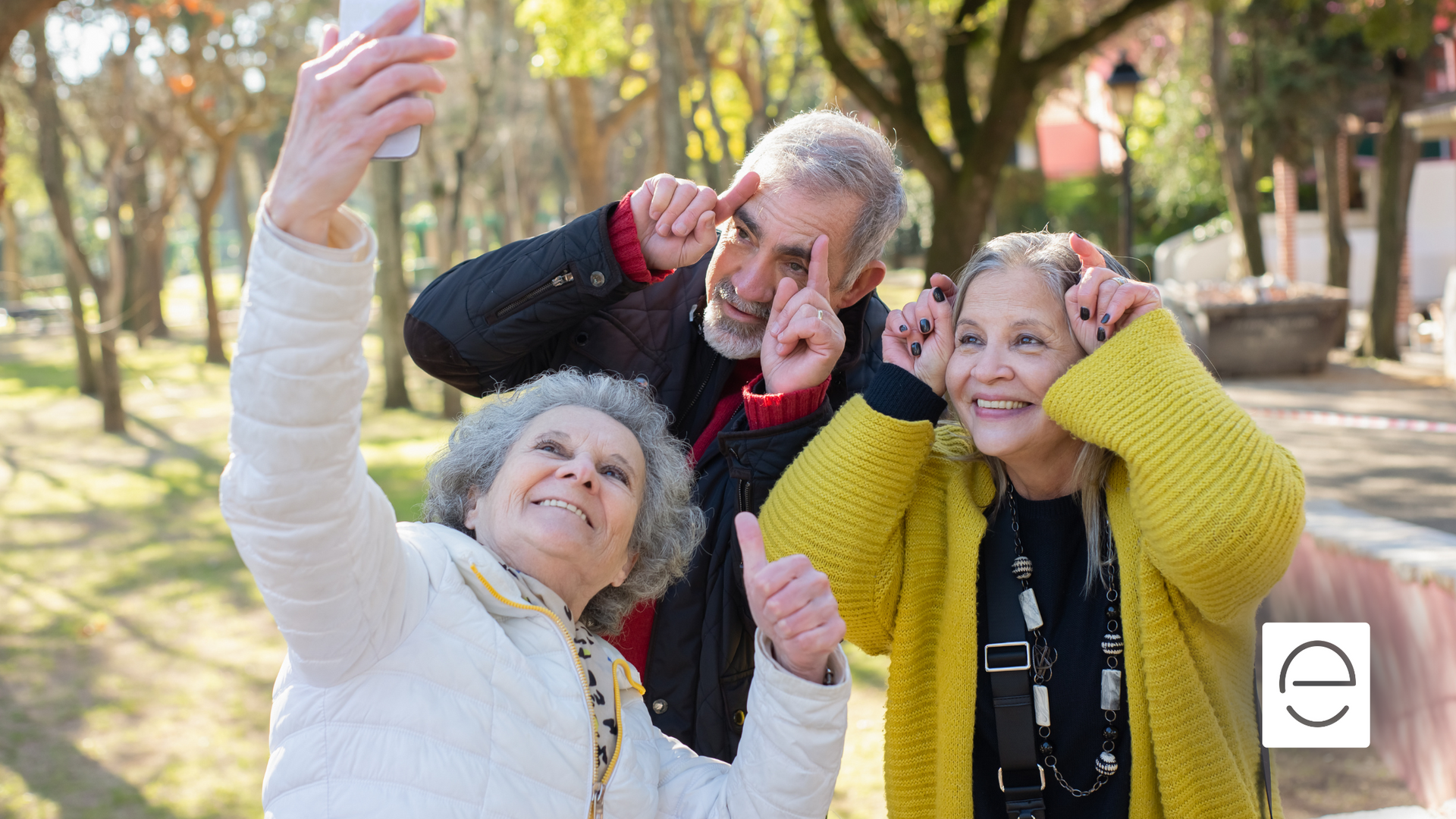 A group of elderly people are taking a selfie in a park.