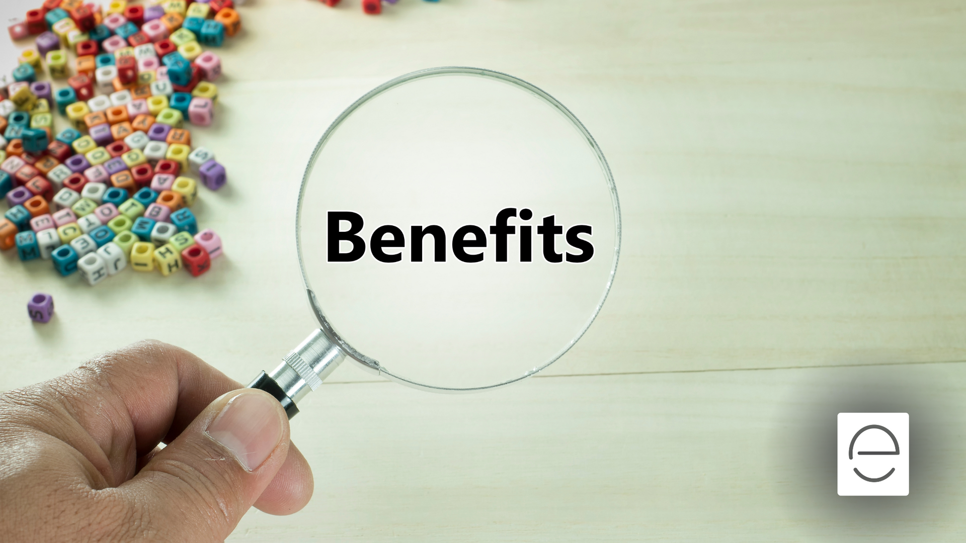 A person is holding a magnifying glass with the word benefits written on it.