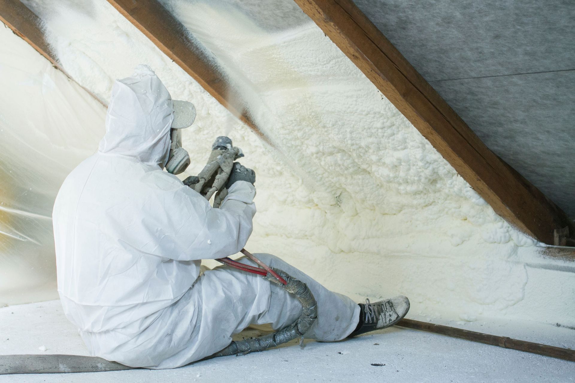 Worker applying foam in attic, showcasing home insulation services for better energy efficiency. Worker applying foam in attic, showcasing home insulation services for better energy efficiency.