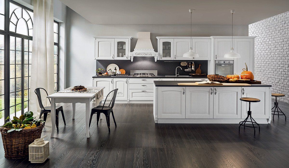 Una cucina con mobili bianchi, un tavolo e sedie.