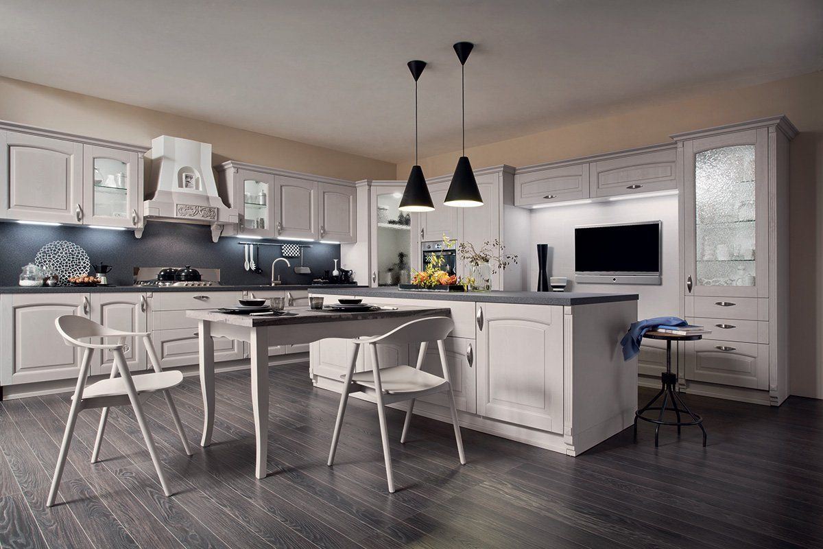 Una cucina con mobili bianchi, un tavolo e sedie.