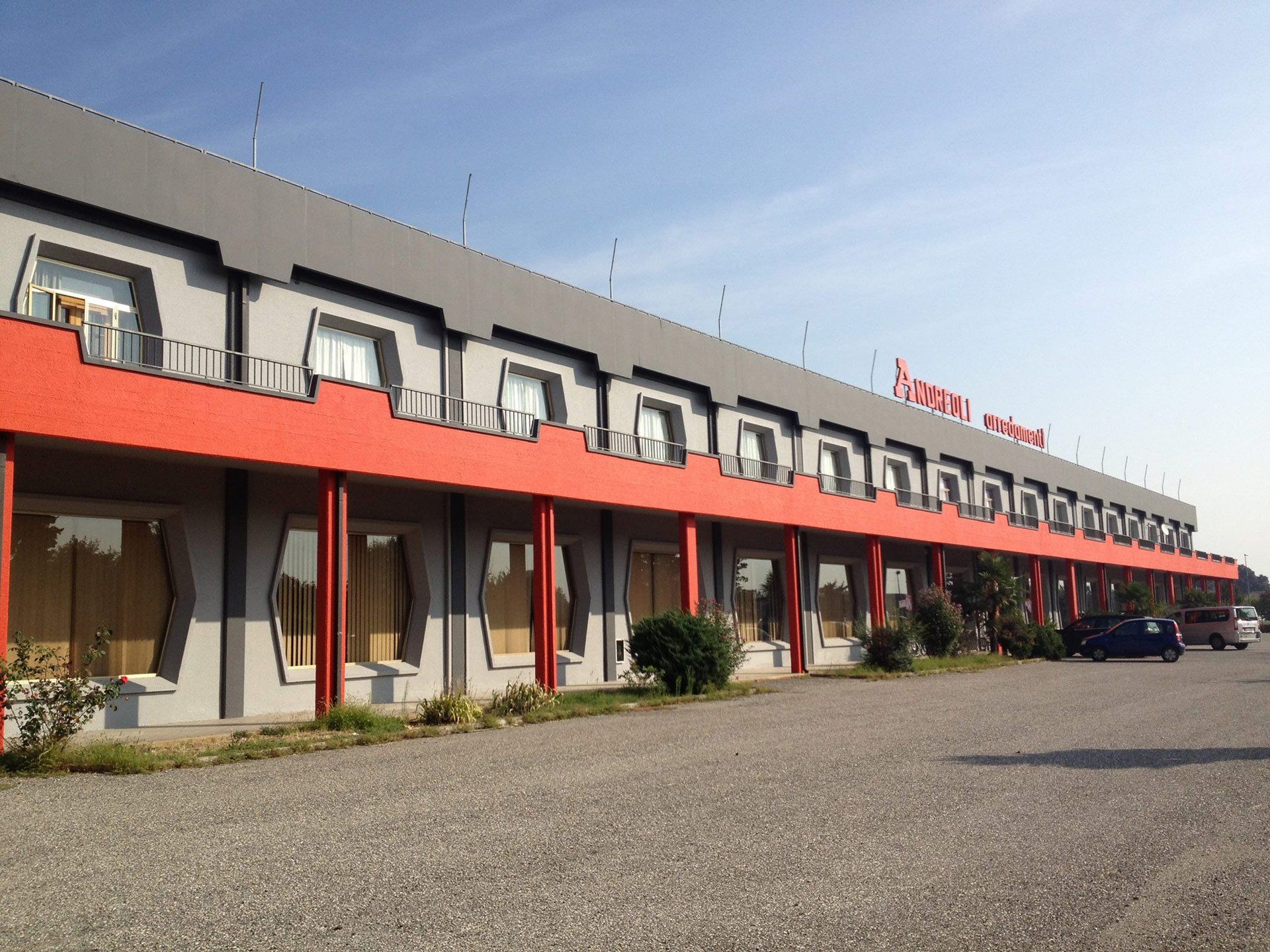 Un grande edificio con molte finestre e una fila di auto parcheggiate di fronte