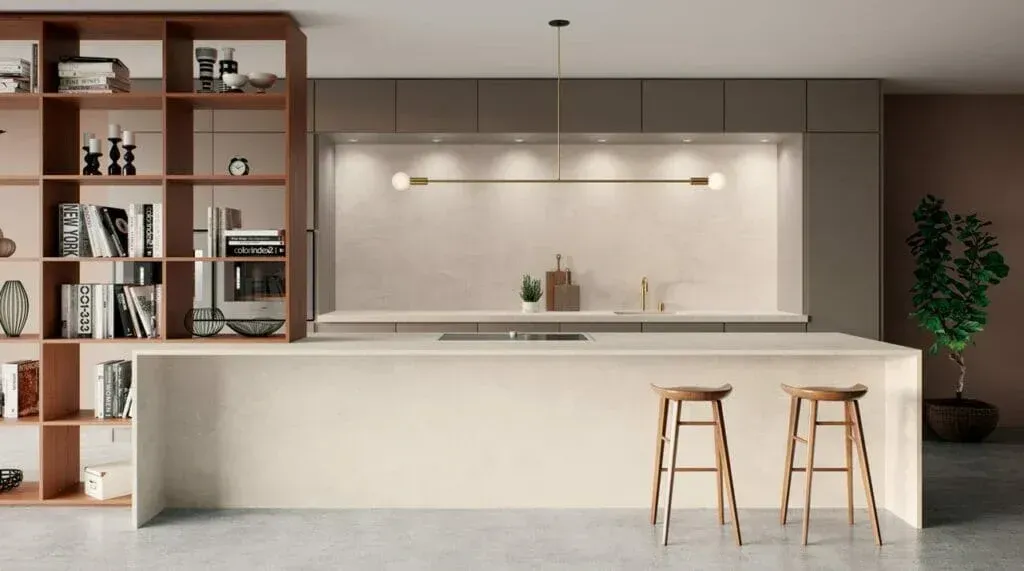 Modern kitchen with light-colored cabinets, island, and wooden stools, along with a built-in bookshelf on the left.