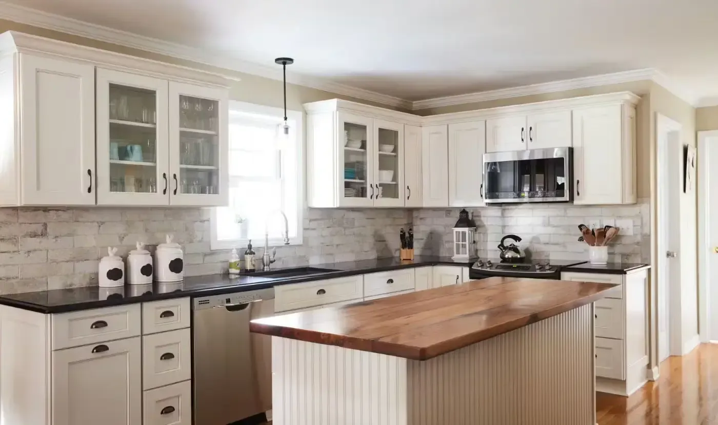 White kitchen with island, black counters, white cabinets, and a wood countertop.