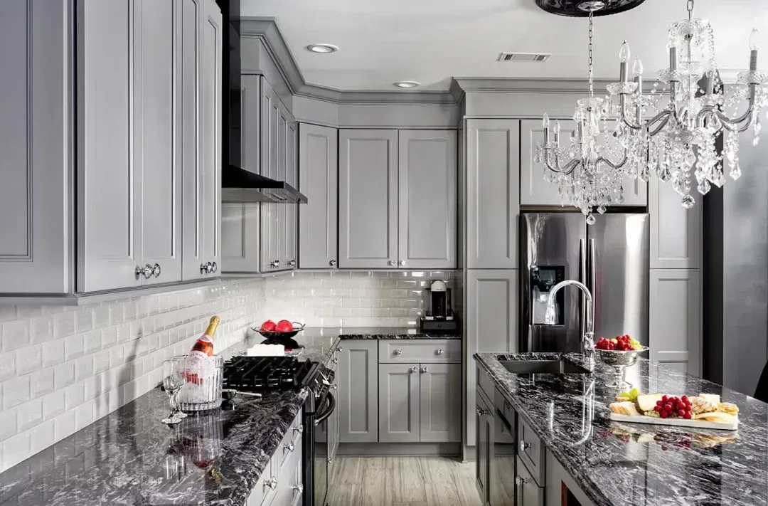 Gray kitchen with granite countertops, stainless steel appliances, and a chandelier.