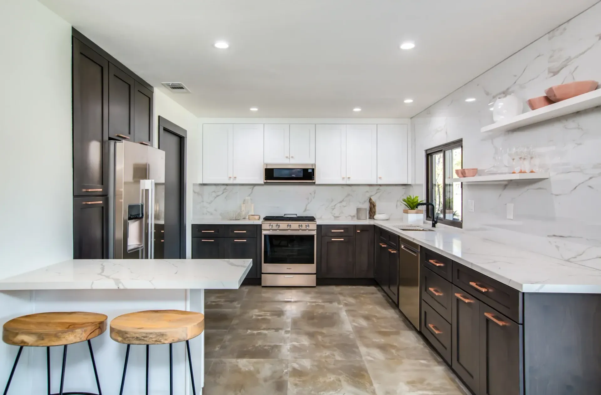 Modern kitchen with white and dark cabinets, marble backsplash, and wooden stools.