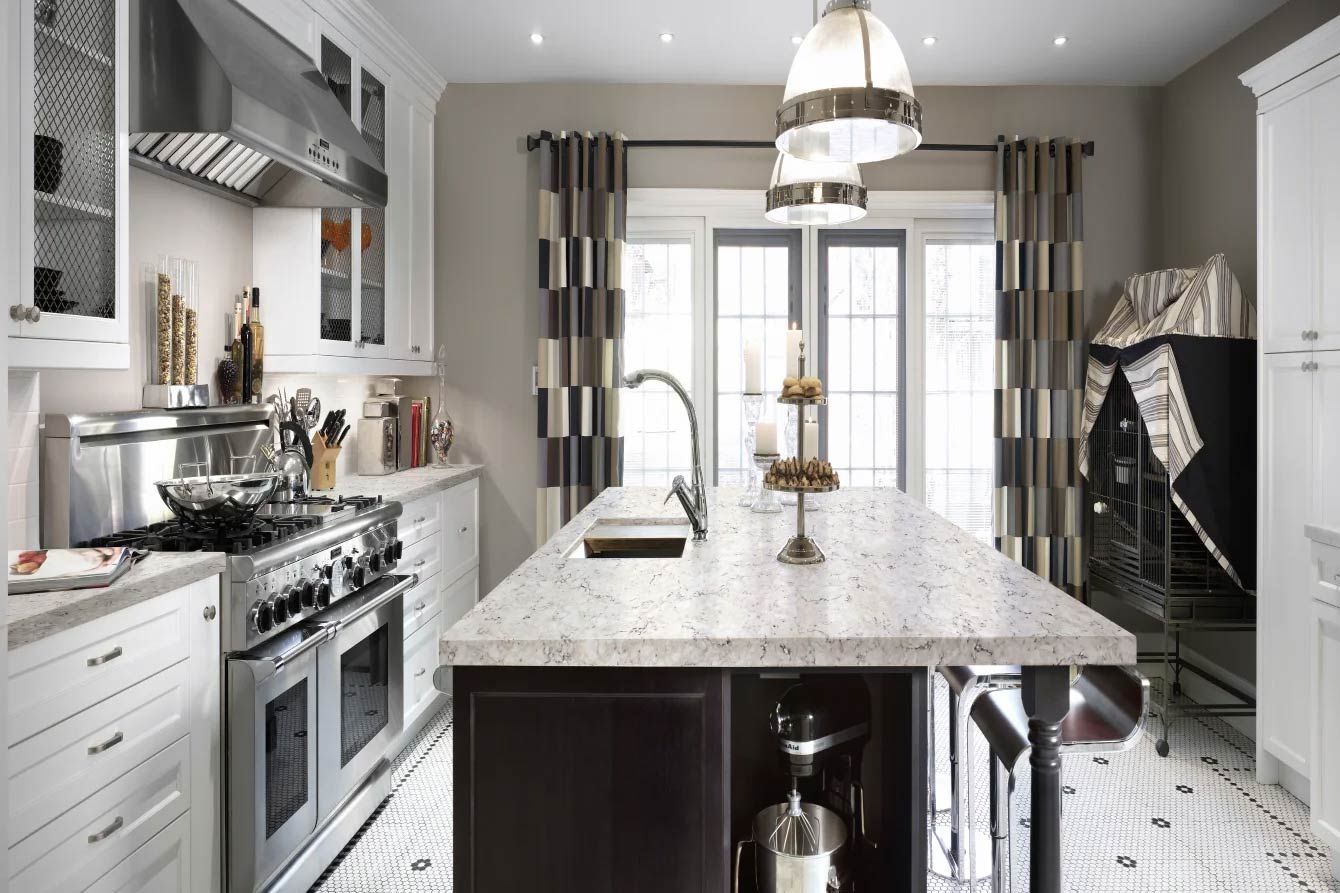Elegant kitchen with white cabinetry, dark island, and marble countertops.