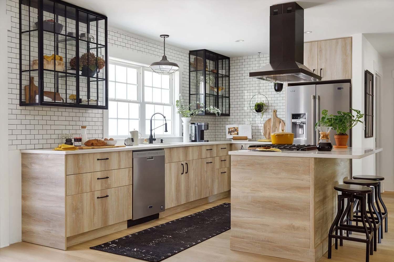 Modern kitchen with light wood cabinets, white brick wall, stainless steel appliances, and black accents.