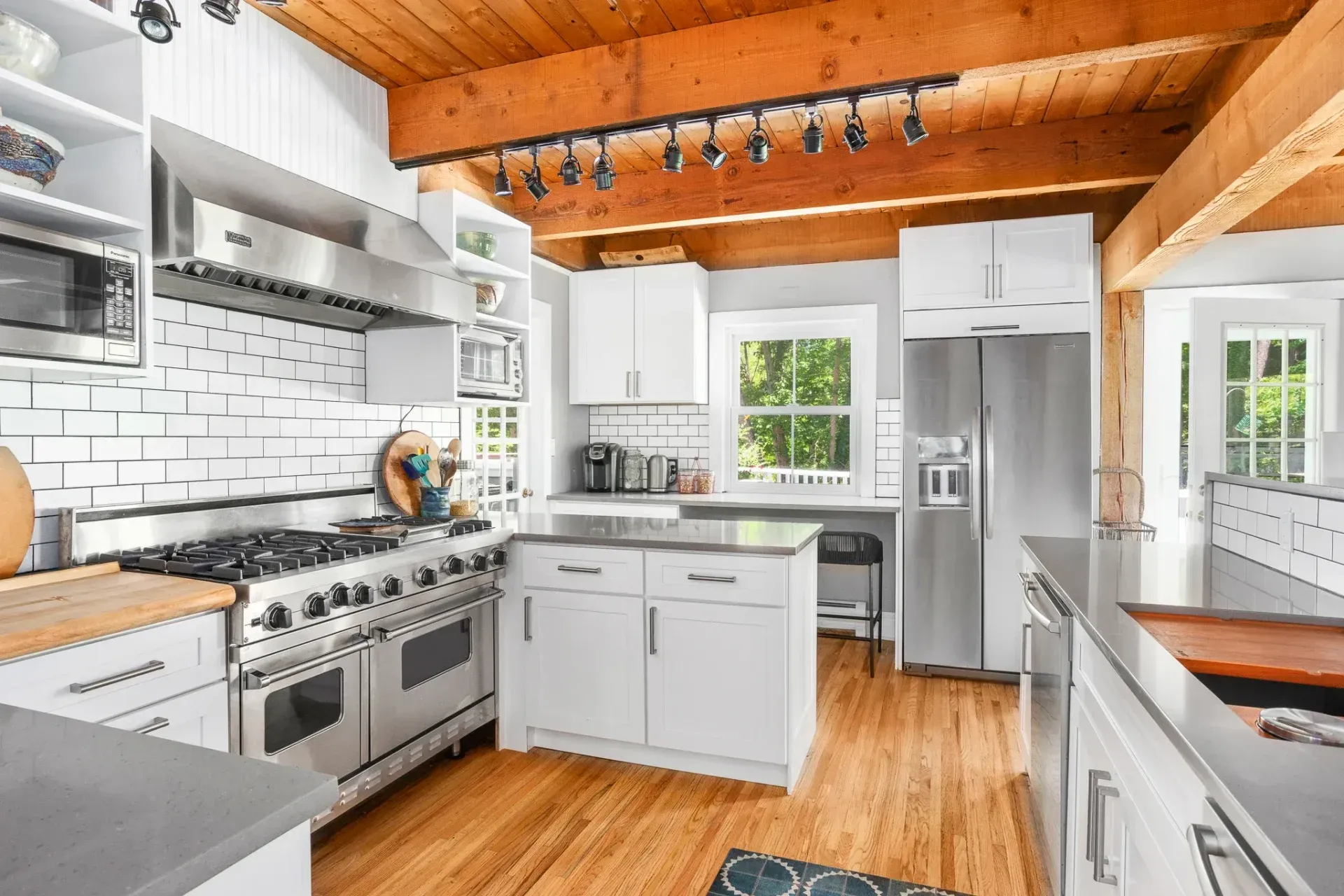 Bright kitchen with white cabinets, stainless steel appliances, and wood ceiling.