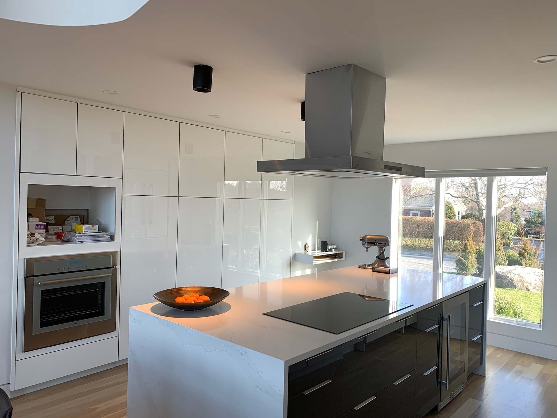 Modern white kitchen with island, stainless steel appliances, and natural light from windows.