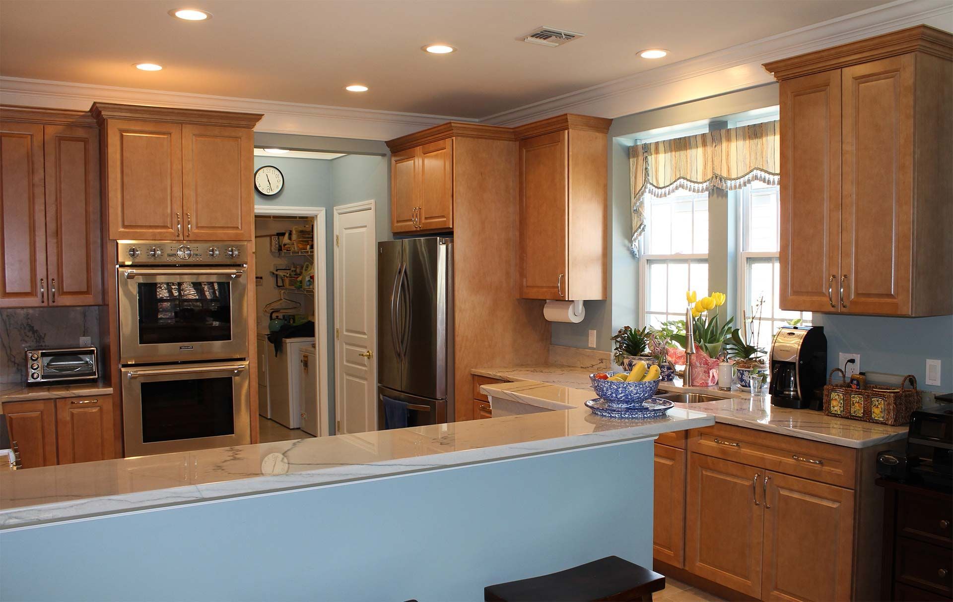 Kitchen with light brown cabinets, stainless steel appliances, and blue walls.