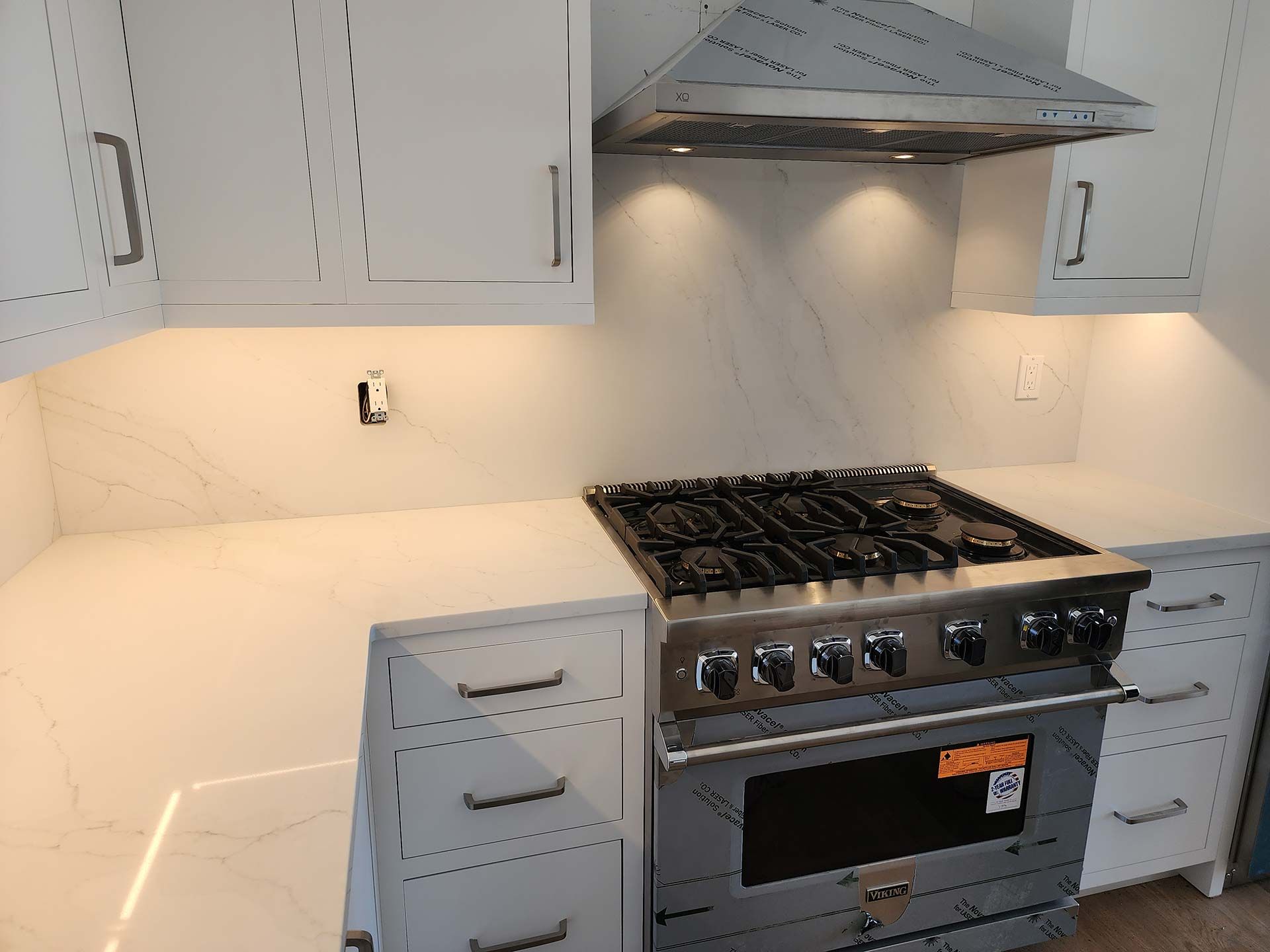 White kitchen with stove, cabinets, and white countertop.