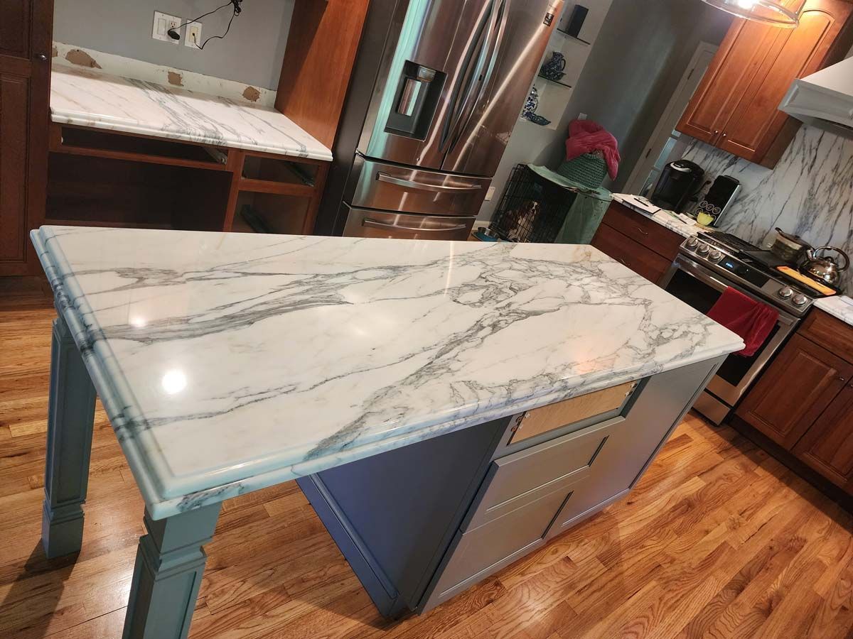 Kitchen with a marble countertop island and cabinetry, in a home setting.