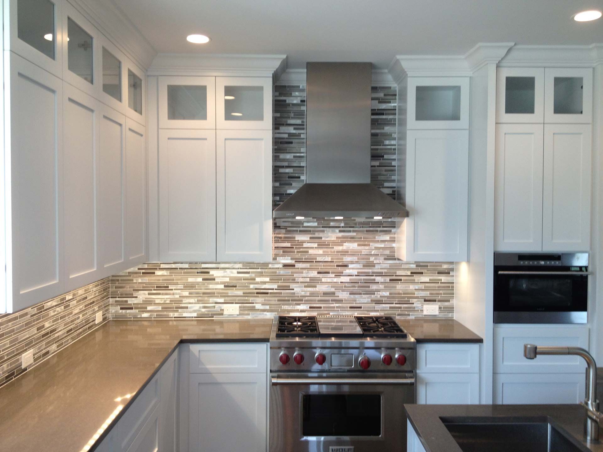 White kitchen with stainless steel appliances and a mosaic backsplash.