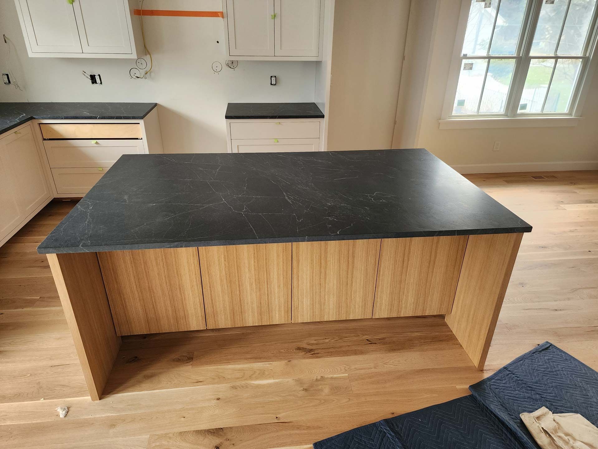 Kitchen island with a black countertop and wood paneling.