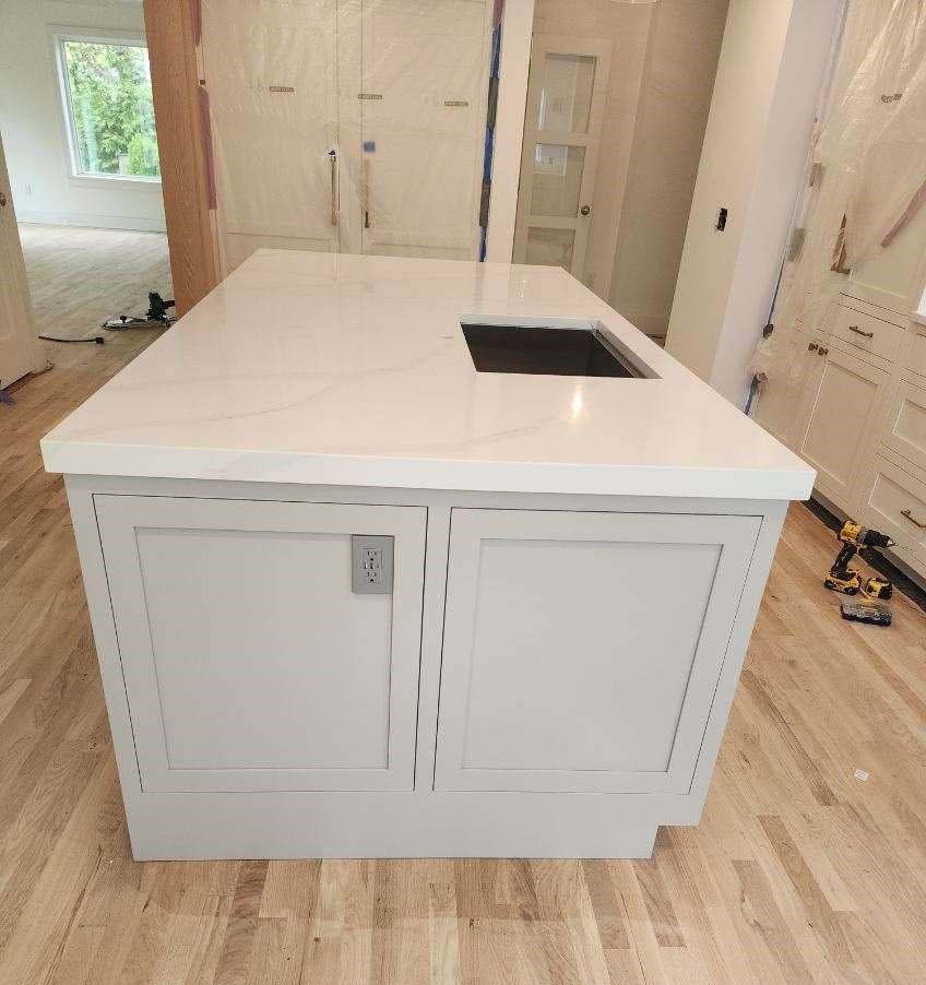 A light gray kitchen island with a white countertop and a sink.