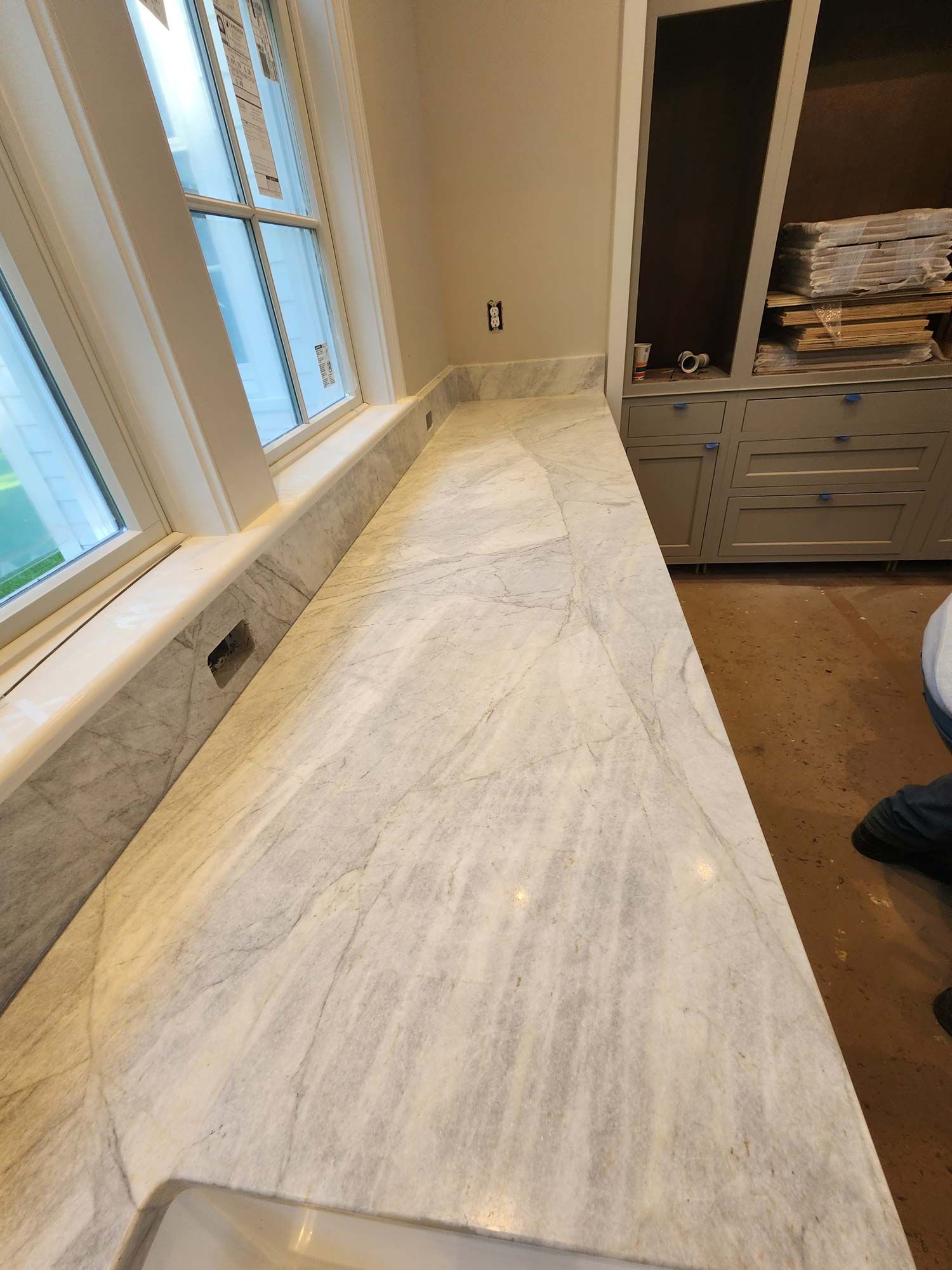 Marble countertop beside a window with built-in outlets, next to a cabinet.