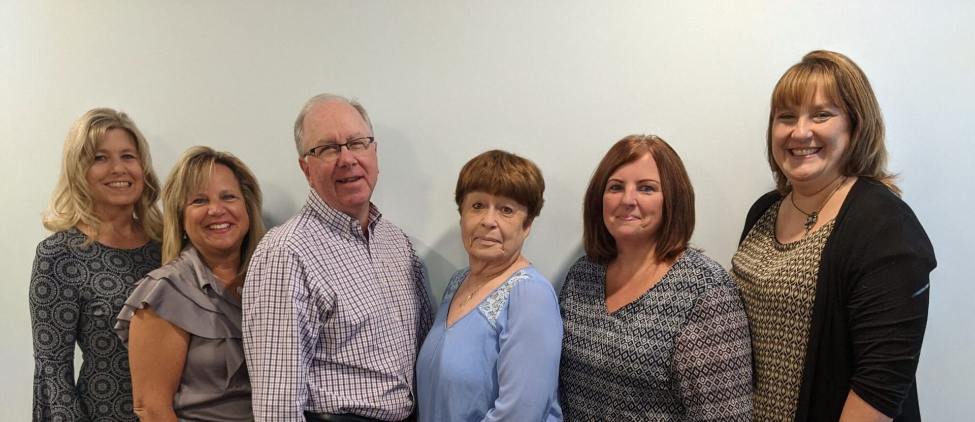 Group photo of six people against a white wall, UPDATE in red at the top.