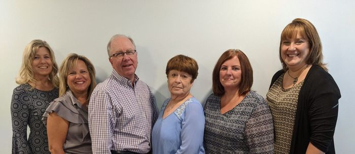 Group photo of six people against a white wall, UPDATE in red at the top.