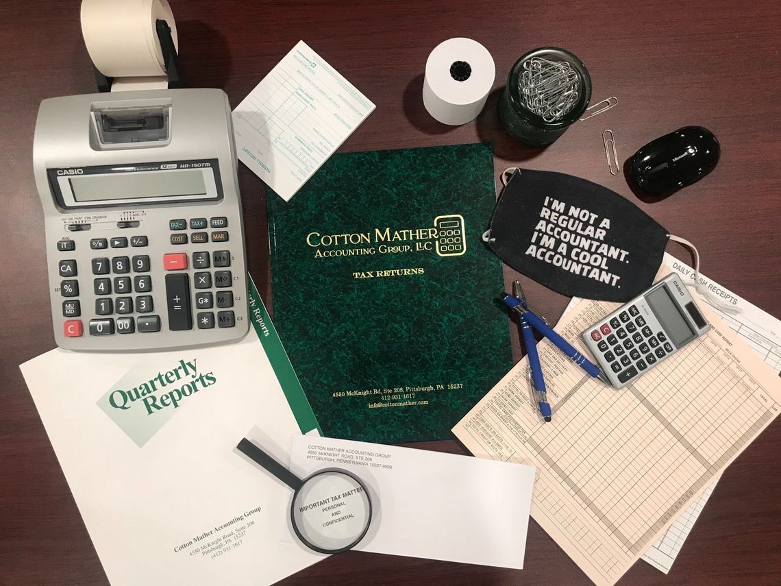Desk with accounting supplies including calculator, receipts, and a face mask.