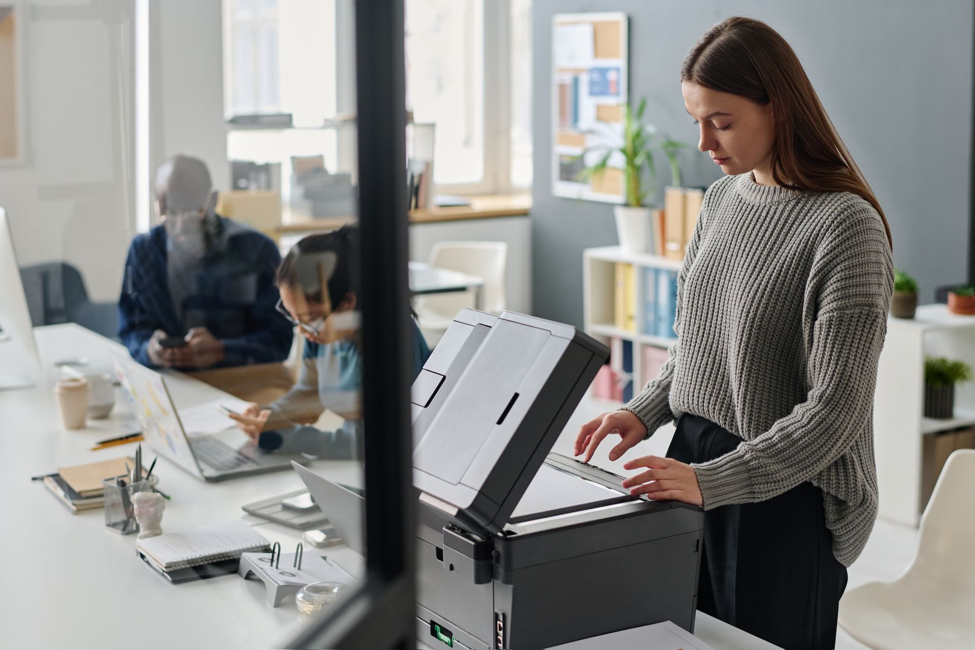 A woman is using a printer in an office.