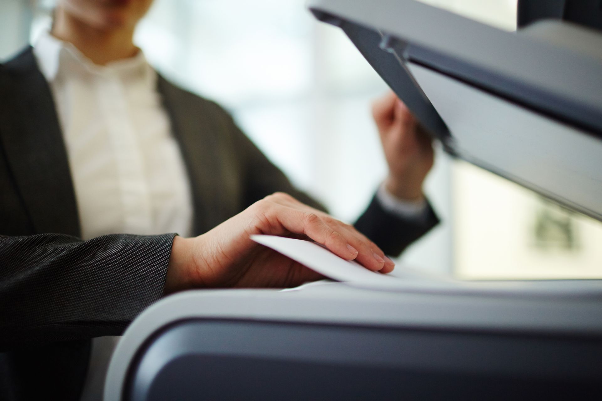 A person is using a printer to scan a piece of paper