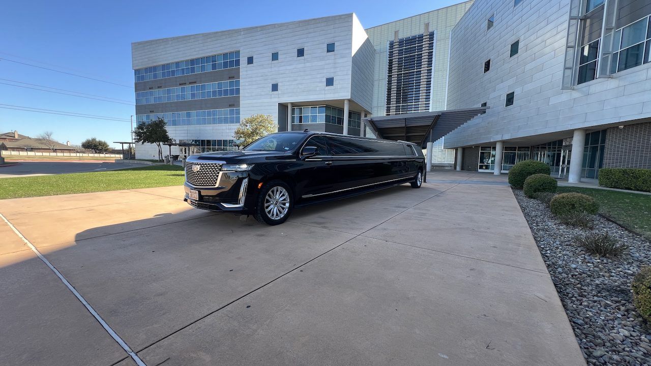 A black limousine is parked in front of a building.