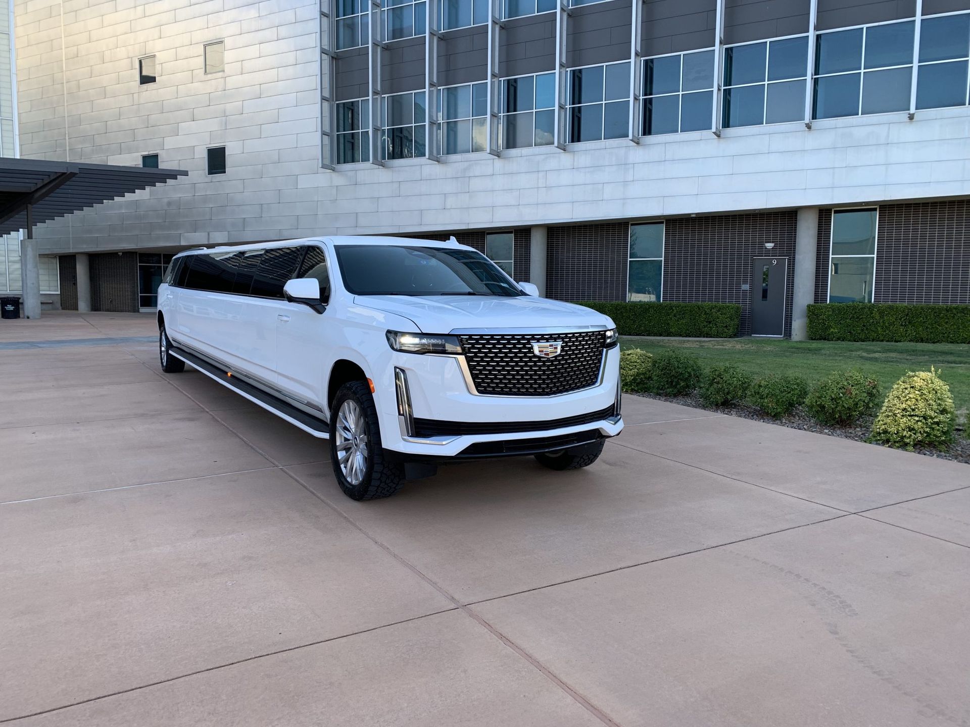 A white limousine is parked in front of a building.