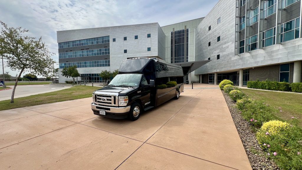 A black limousine is parked in front of a large building.