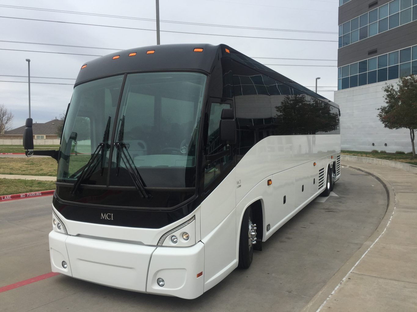 A white and black bus is parked on the side of the road.