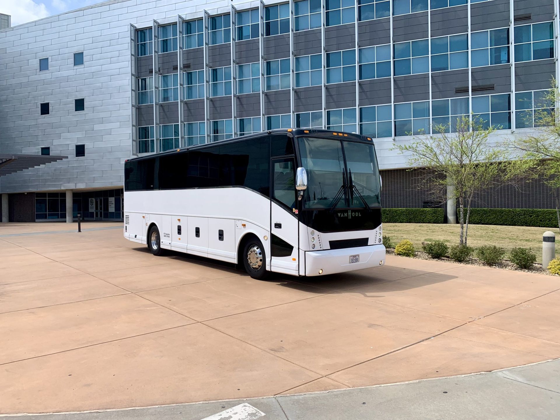 A white bus is parked in front of a large building.