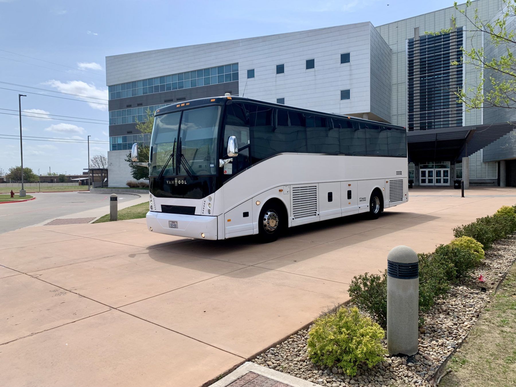 A large white bus is parked in front of a building.