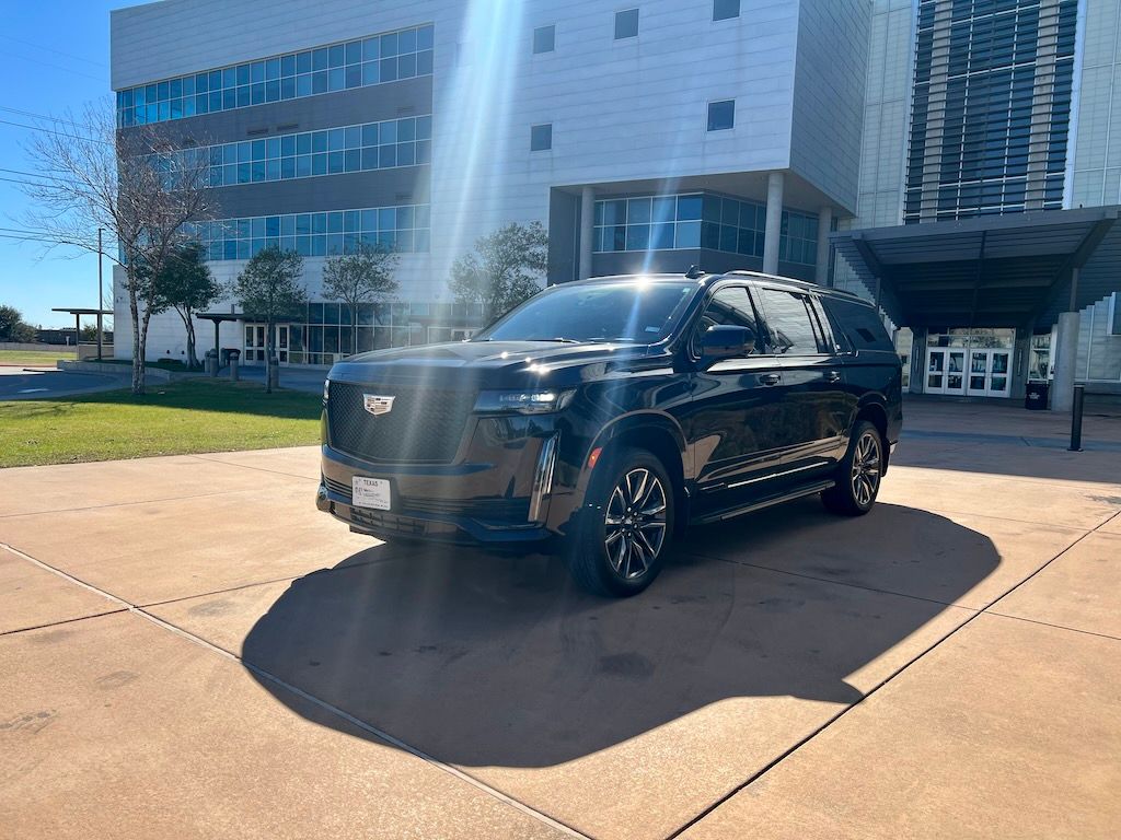 A black cadillac escalade is parked in front of a building.