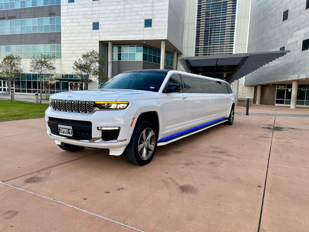 A white limousine is parked in front of a building.