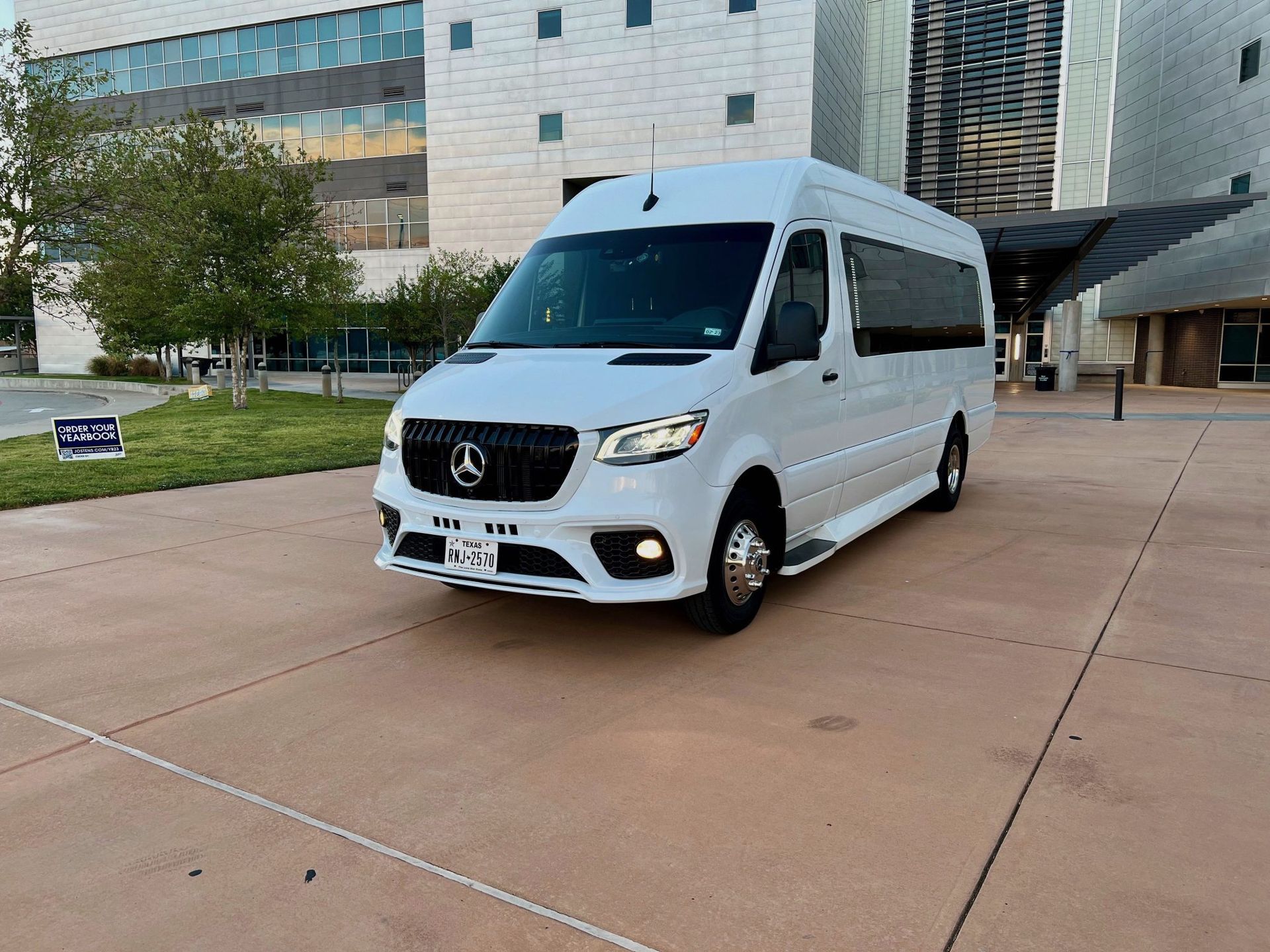 A white van is parked in a parking lot in front of a building.