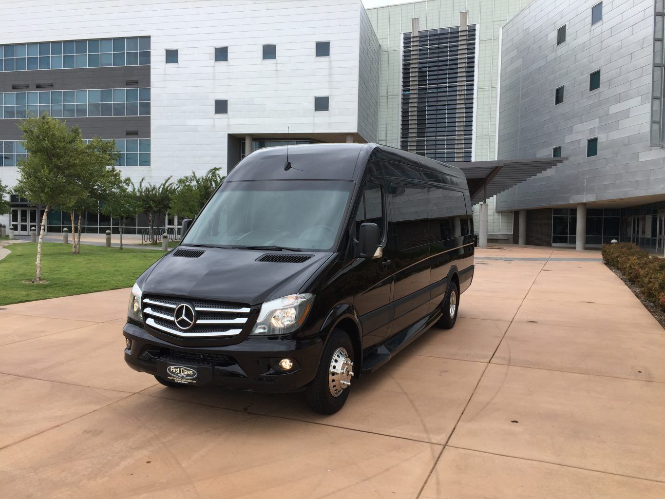 A black mercedes van is parked in front of a building.