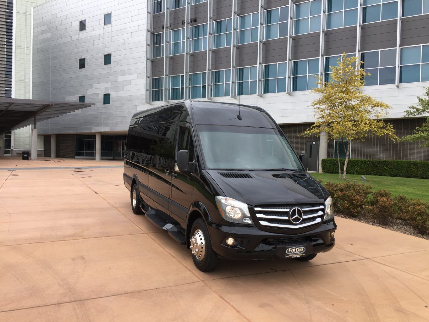 A black mercedes sprinter van is parked in front of a building.