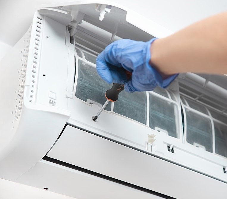 A Person Wearing Blue Gloves Is Fixing An Air Conditioner — Marty Nelson Refrigeration & Air Conditioning In Dubbo, NSW
