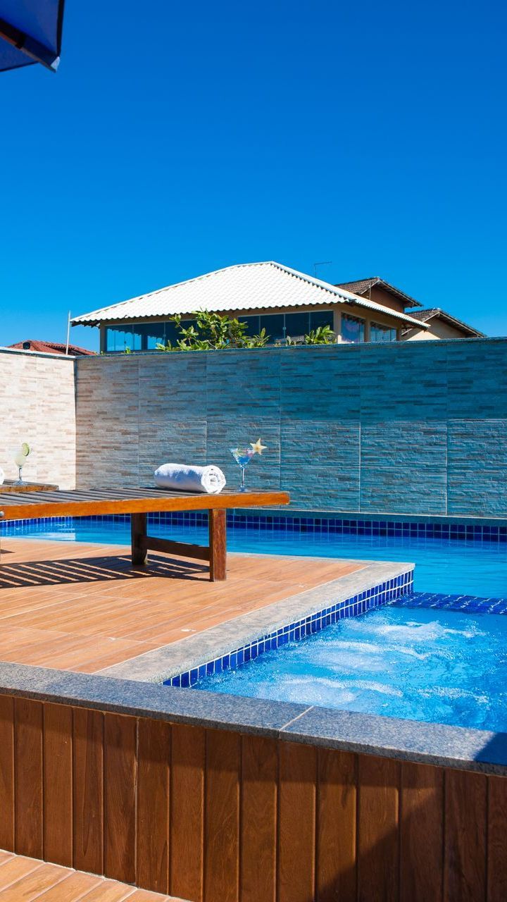 Há uma piscina com jacuzzi no meio. Pousada Pau Brasil
