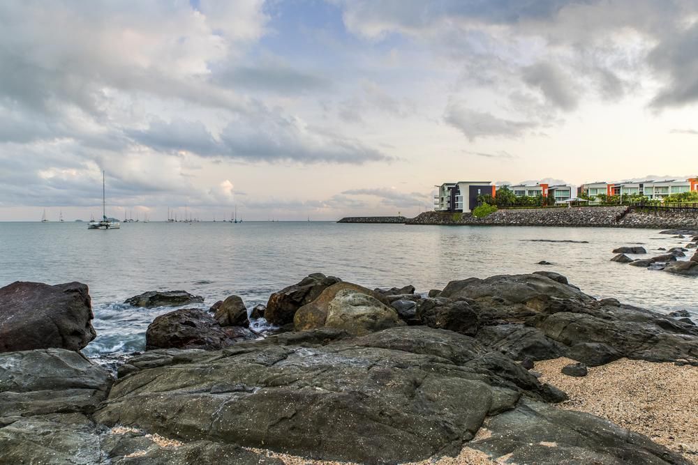A Boat Is Floating on The Water Near a Rocky Shoreline — Tropical Locksmiths in Cannonvale, QLD