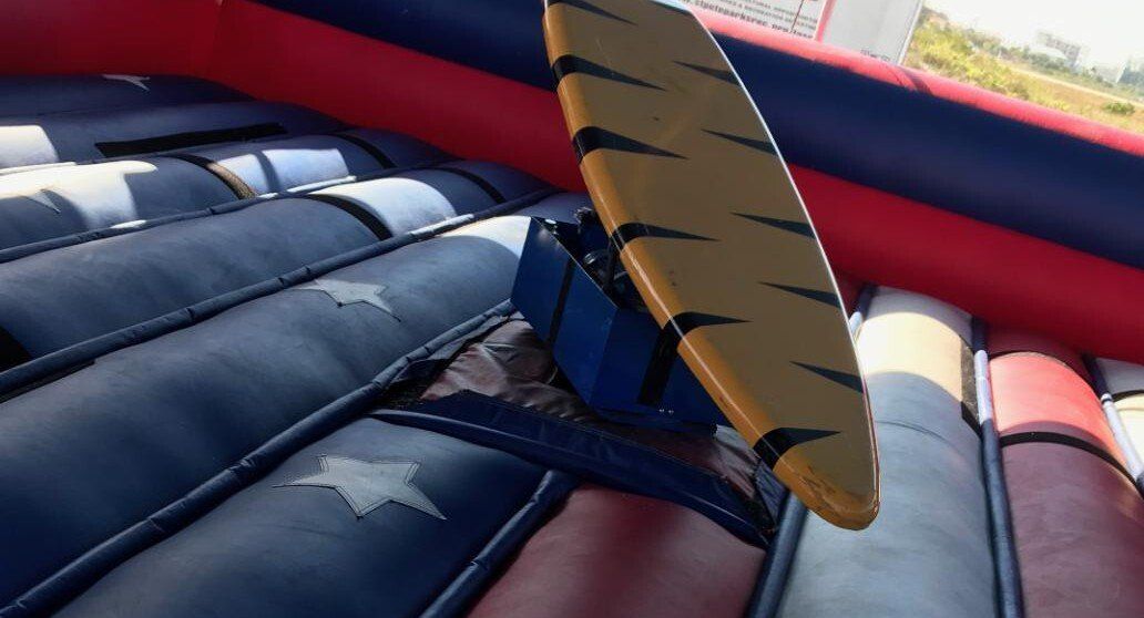 Surfboard simulator ride with mechanical motion and padding.