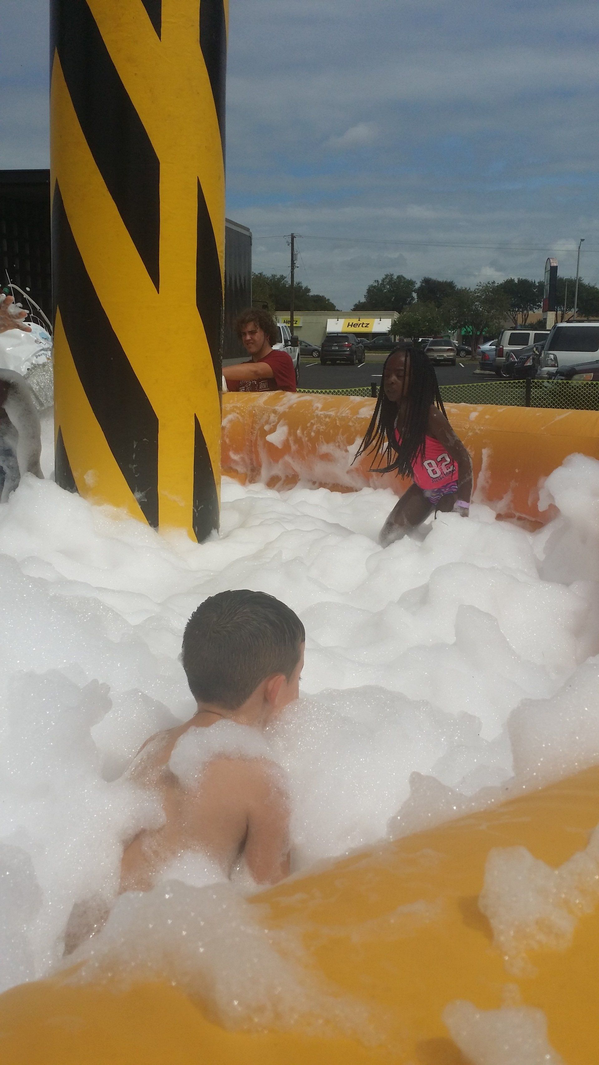 People playing in a foam-covered area with bubbles floating around.