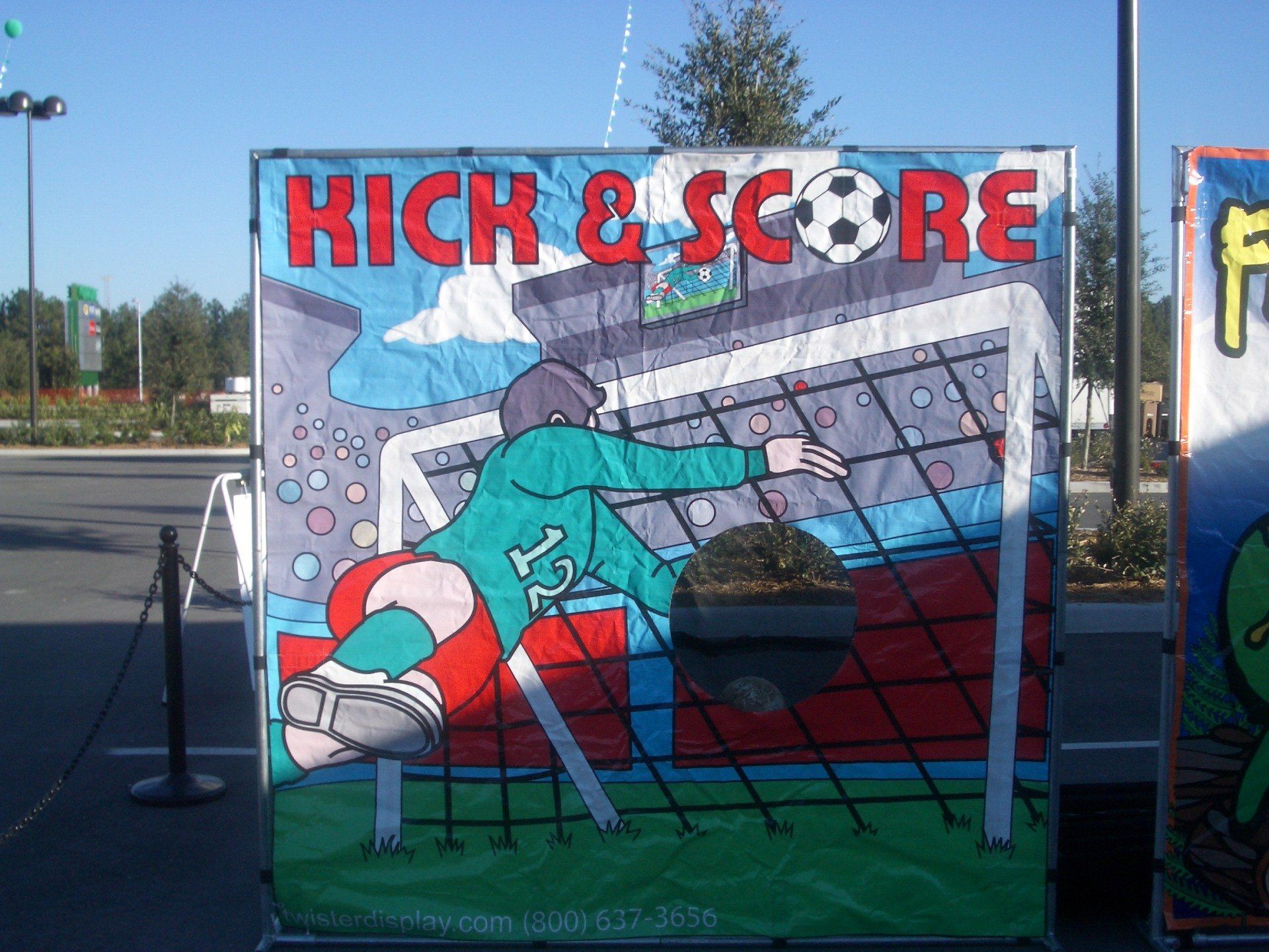  A carnival-style soccer game with a large backdrop featuring a goalie diving to stop a shot, 