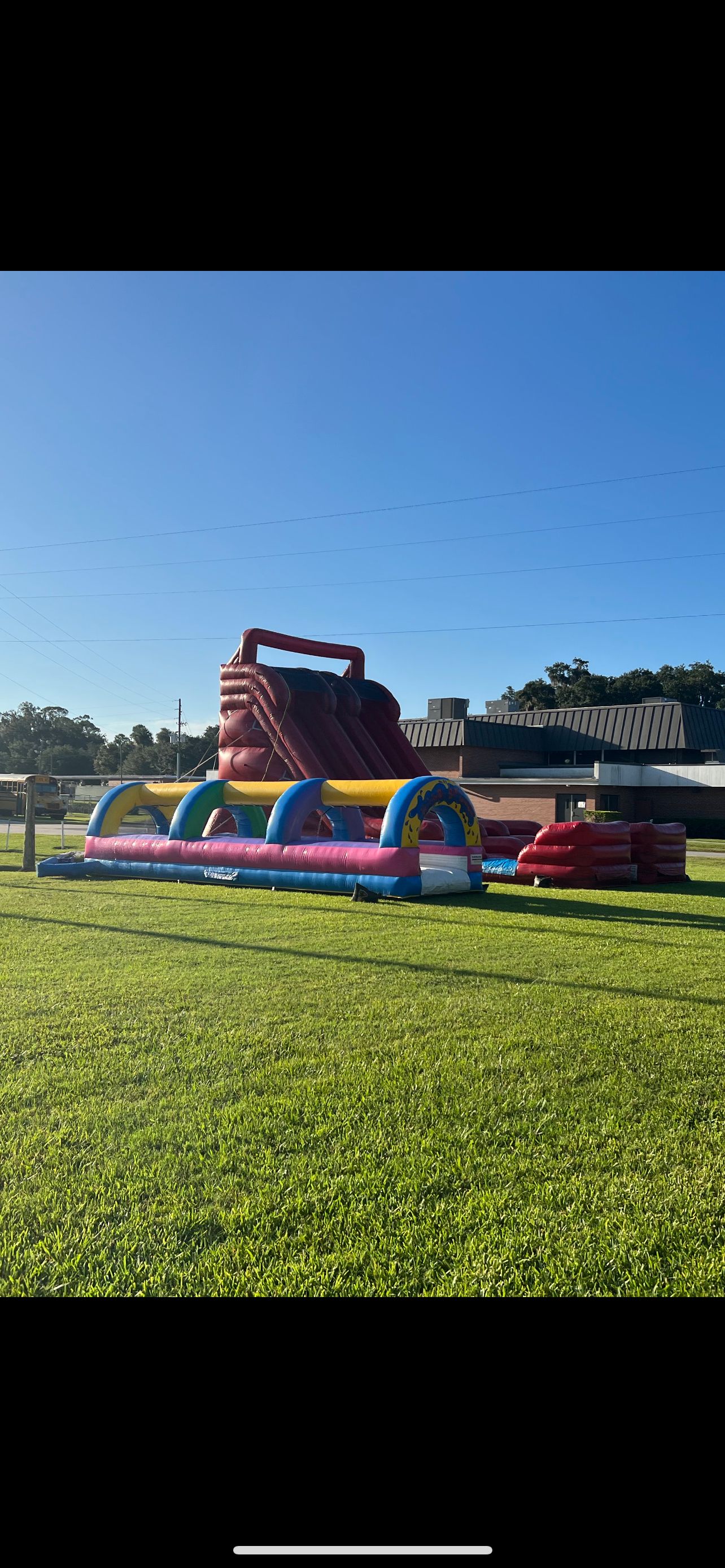 Long inflatable water slide with kids and adults splashing down.