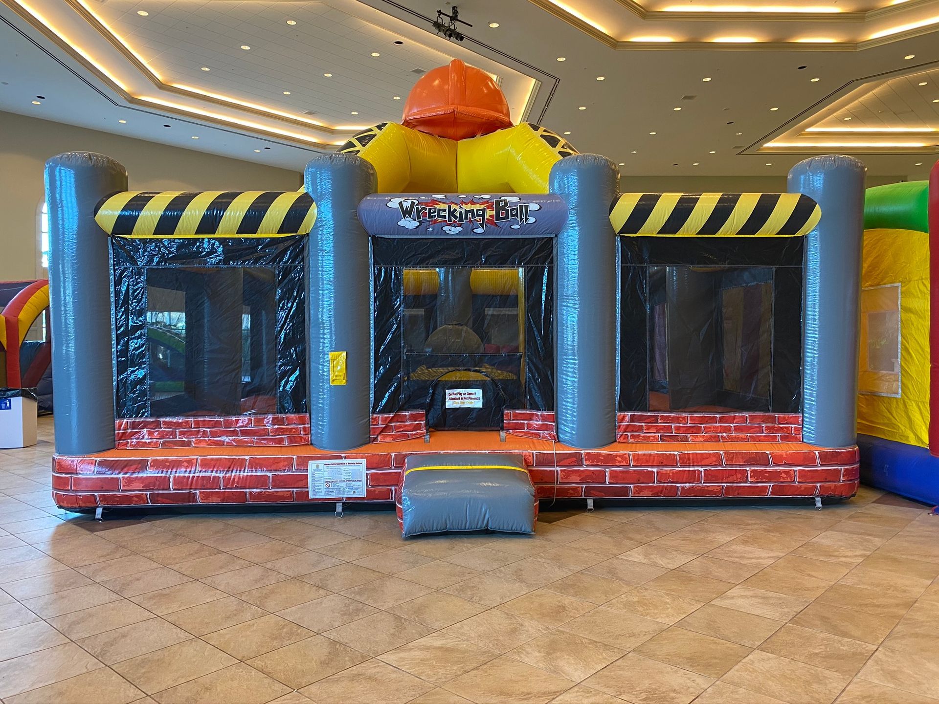  Inflatable wrecking ball game with players balancing and dodging.