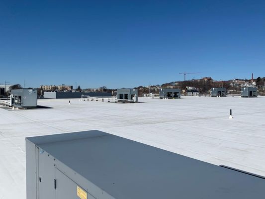 A wide-angle shot of a large-scale white rooftop installation with multiple grey HVAC units under a clear blue sky.
