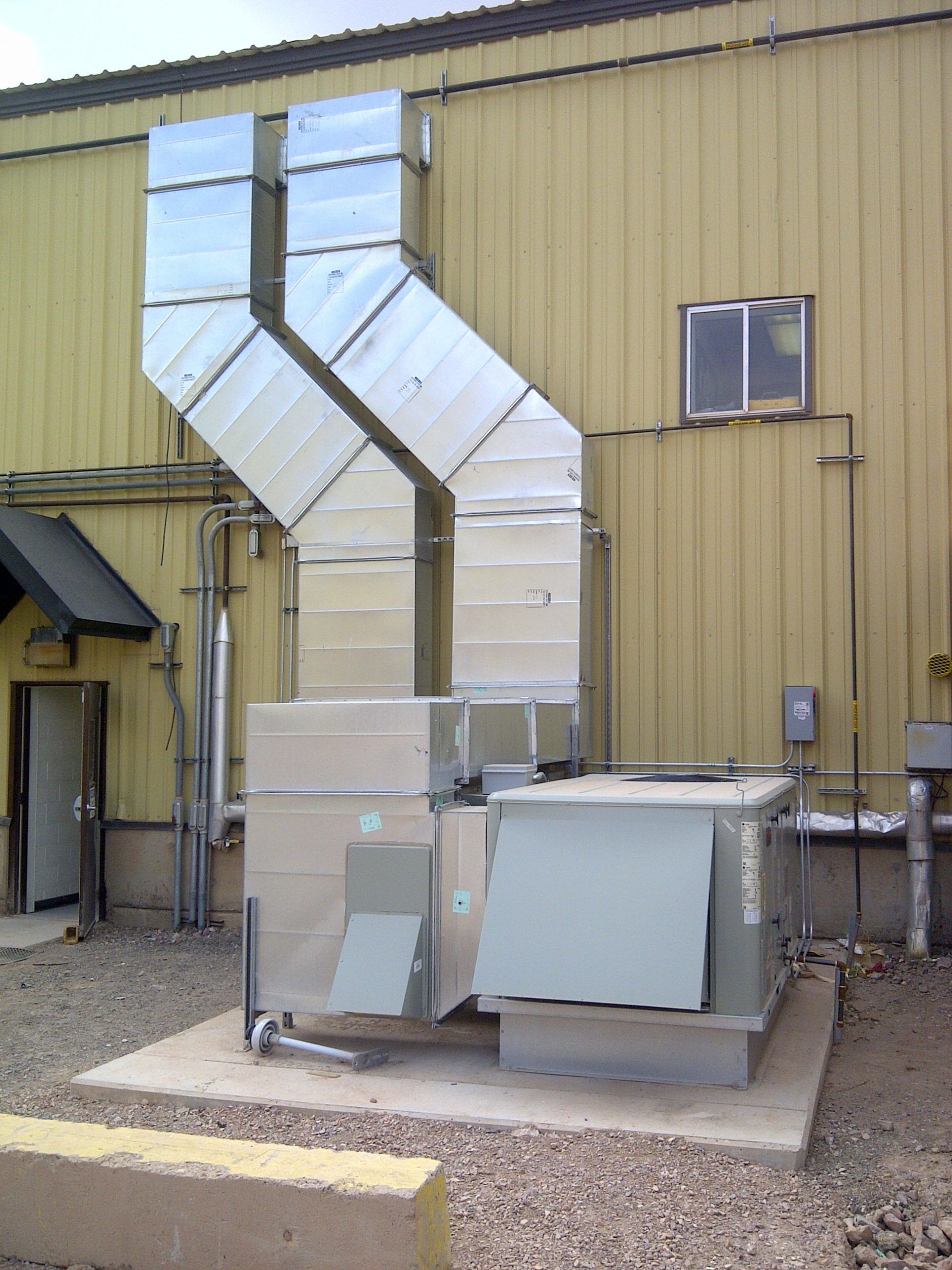 Series of wall-mounted AC condenser units installed on the exterior of a commercial building.