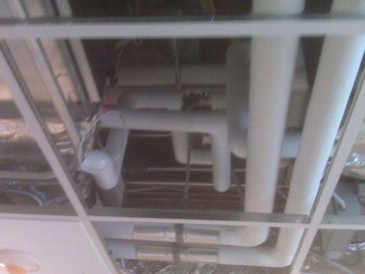 A close-up view of white insulated HVAC piping installed within a ceiling grid framework.